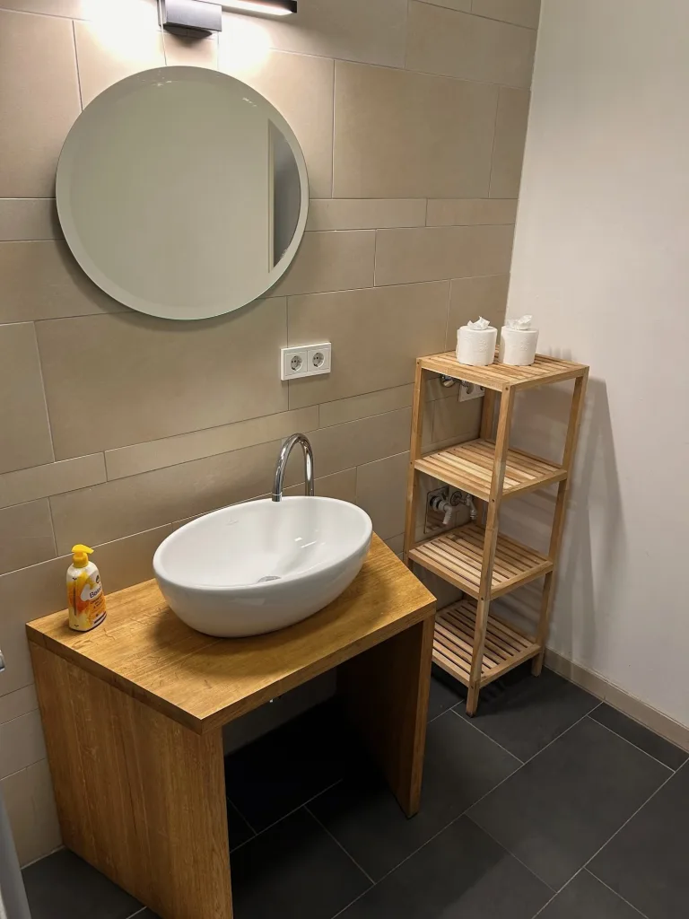 Badezimmer der Kuhviertelstube mit Aufsatzwaschbecken und rundem Spiegel