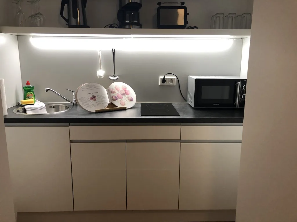 Küchenzeile der Wohnung 2.1 mit Mikrowelle, Wasserkocher und Unterbaubeleuchtung