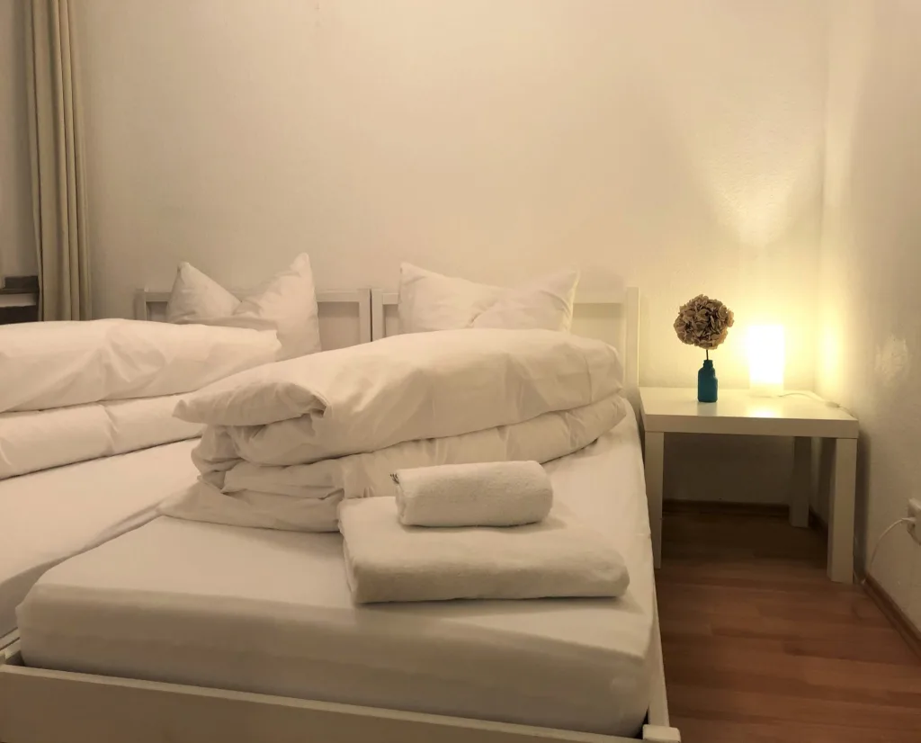 Schlafbereich der Wohnung 2.1 mit bezogenem Bett und Handtüchern