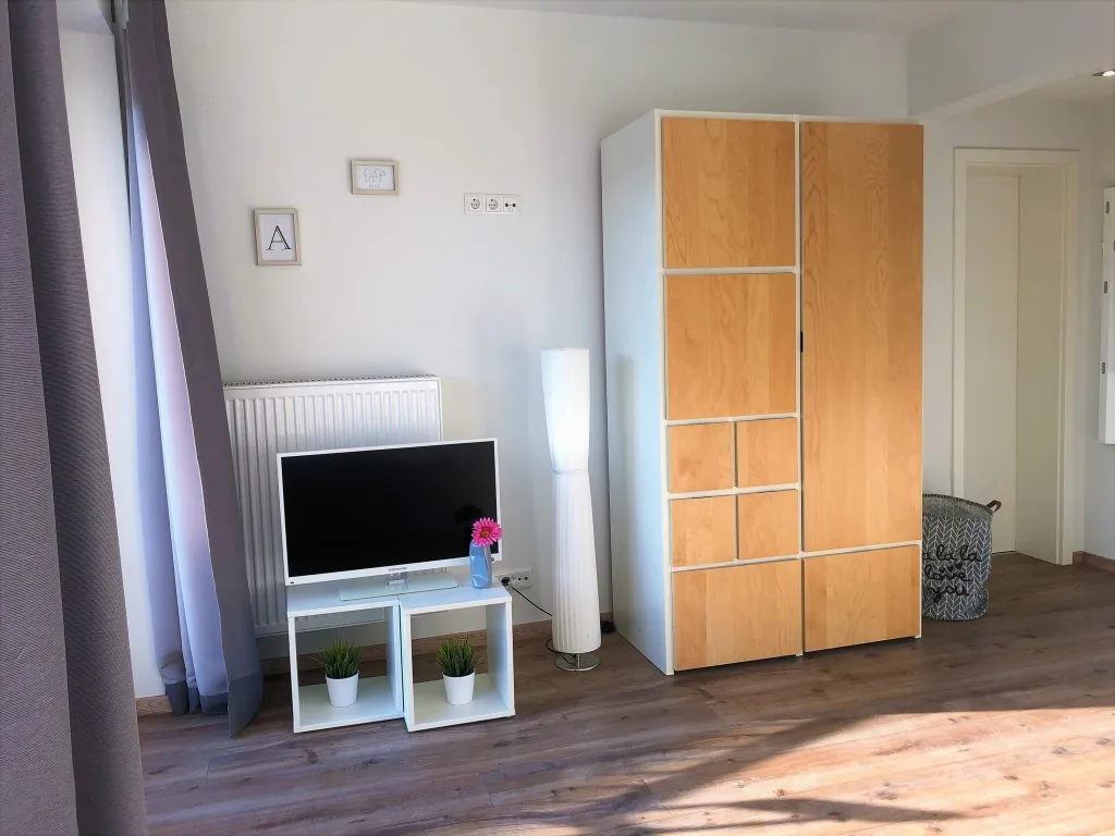 Wohnbereich der Wohnung 2.3 mit Fernseher und Kleiderschrank