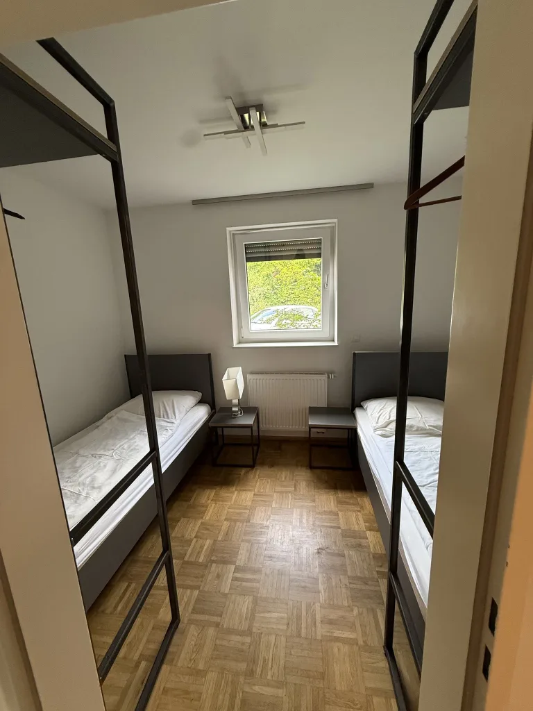 Schlafbereich der Wohnung 2 mit zwei Einzelbetten hinter der Glaswand