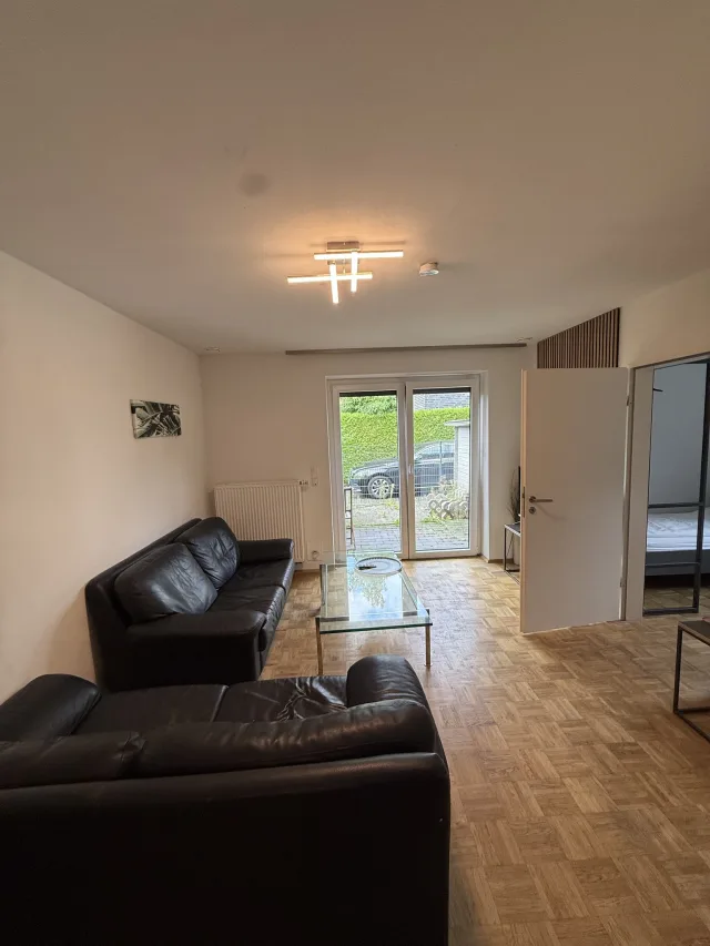 Wohnbereich der Wohnung 2 mit Ledersofa und Tür zur eigenen Außenterrasse