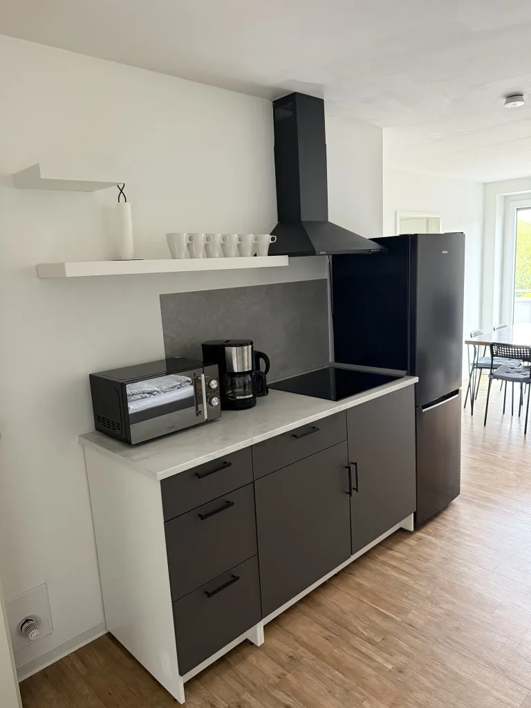 Küchenzeile der Wohnung 4 mit Kochfeld, Mikrowelle, Filterkaffeemaschine und Kühlschrank