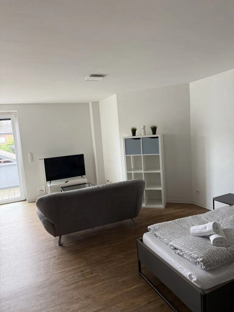 Wohnbereich der Wohnung 4 mit Sofa, Fernseher und Regal
