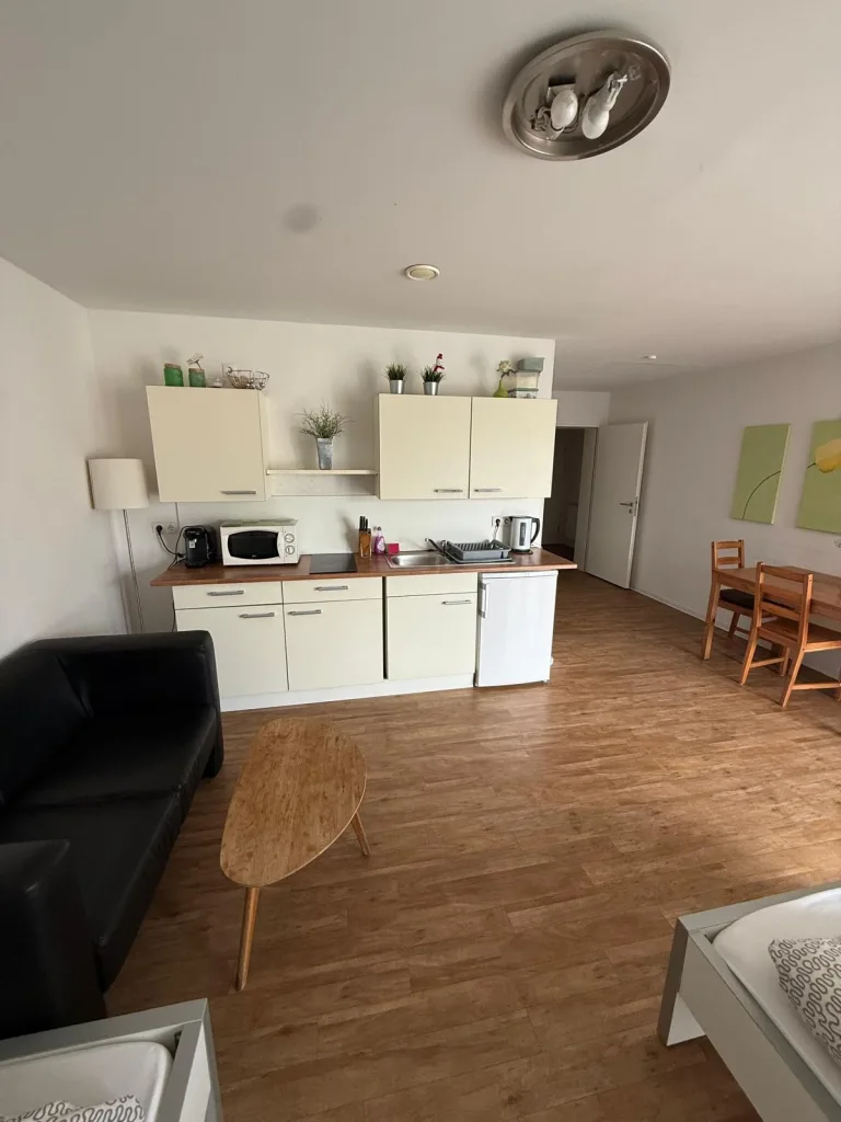 Wohnbereich der Wohnung 6 mit Sofa und Couchtisch vor der Küchenzeile