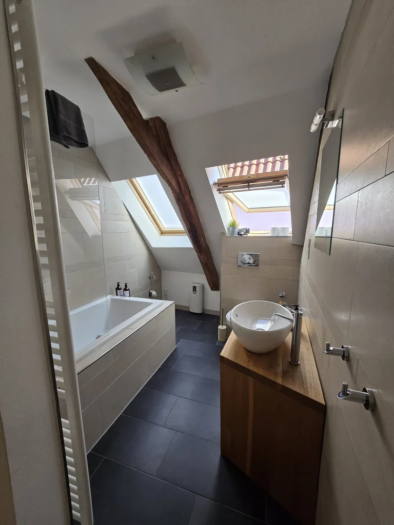 Badezimmer der Giebelkoje mit Badewanne, Aufsatzwaschbecken und Dachfenster