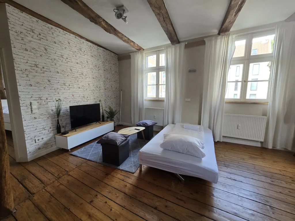 Wohnbereich der Leezen mit Sofa, Fernseher und weiß geschlämmter Backsteinwand