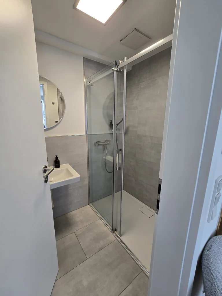 Badezimmer von Family & Friends mit Dusche und rundem Spiegel