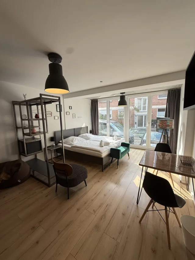 Wohnbereich des Lichtnests mit Bett, Regal und großer Fensterfront