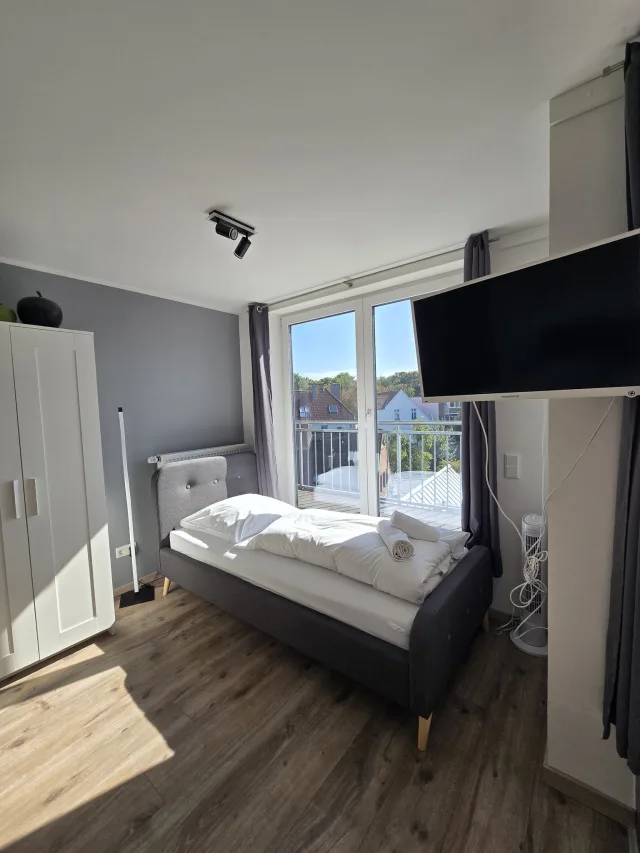 Wohnbereich des Schlossgartens mit Bett, Fernseher und Balkontür