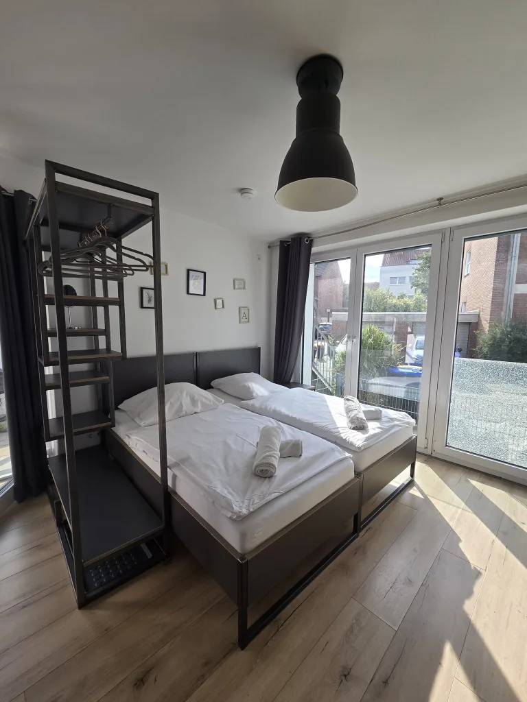 Schlafbereich der Stadtruhe mit Doppelbett an der großen Fensterfront