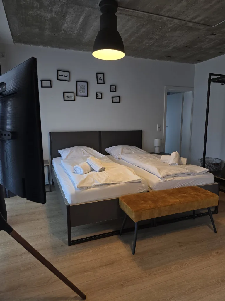 Schlafbereich des Viertelnests mit Doppelbett, Bilderrahmen und Lederbank