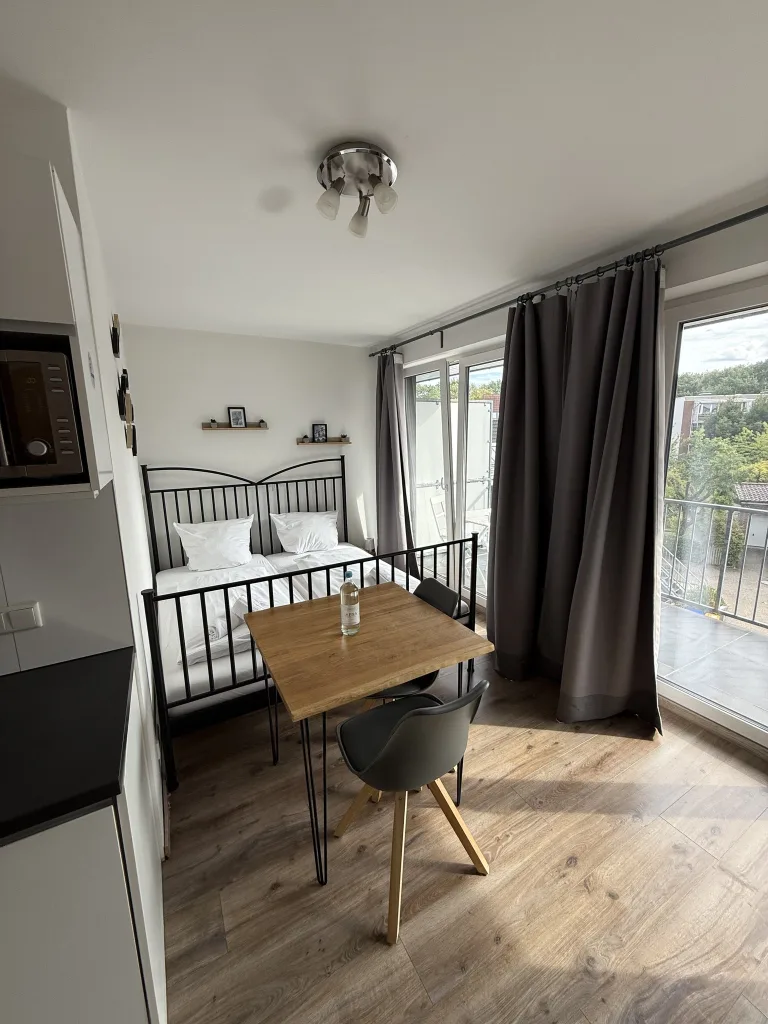 Schlafbereich der Wohnung 2.3 mit Doppelbett und Esstisch an der Balkontür