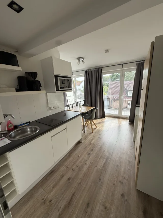 Blick durch die Wohnung 2.3 mit Küchenzeile, Esstisch und Fenster zum Balkon