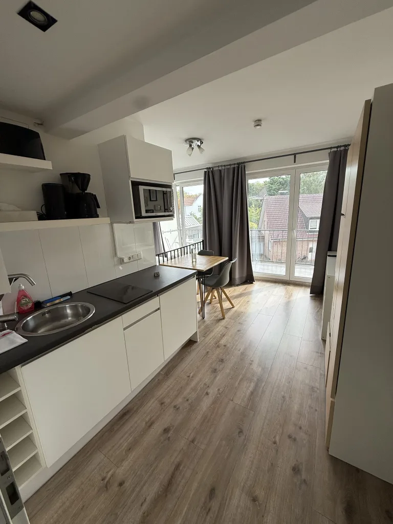 Blick durch die Wohnung 2.3 mit Küchenzeile, Esstisch und Fenster zum Balkon